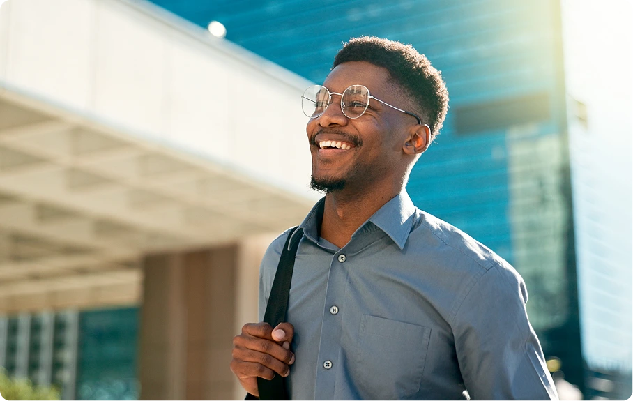 A Black man smiling with a backpack on one of his shoulders