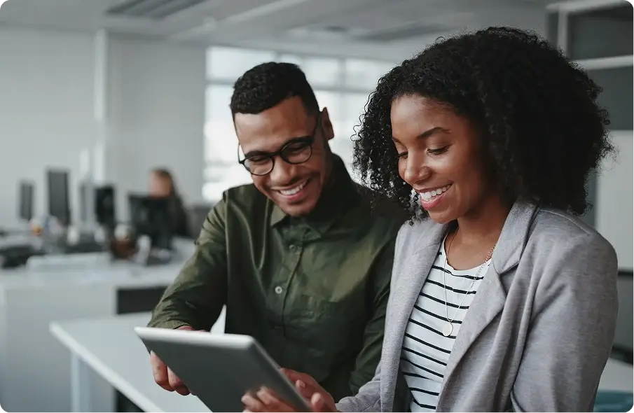 A man and woman smiling at a device as they learn about Unahina Business Solutions