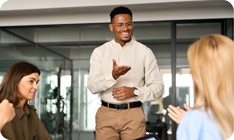 A man standing, talking to two seated women, about How Unahina's specialists in government and corporate procurement help South African companies.
